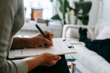 A woman writing in a notebook while sitting on a couch